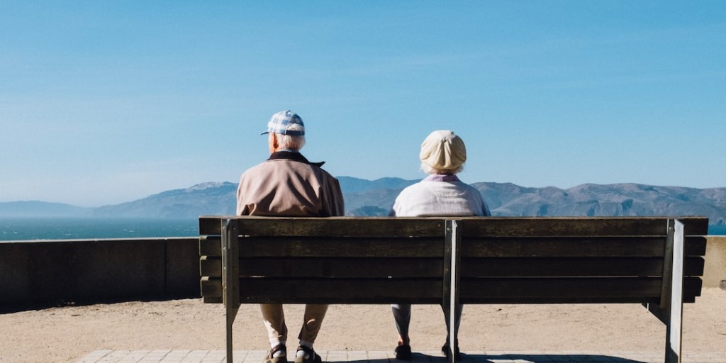 senior citizens sitting together on a park bench looking to the horizon