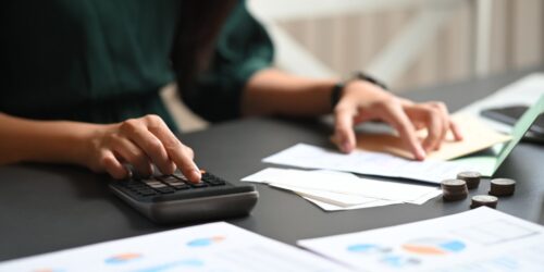 Entrepreneur going through their expenses on a calculator